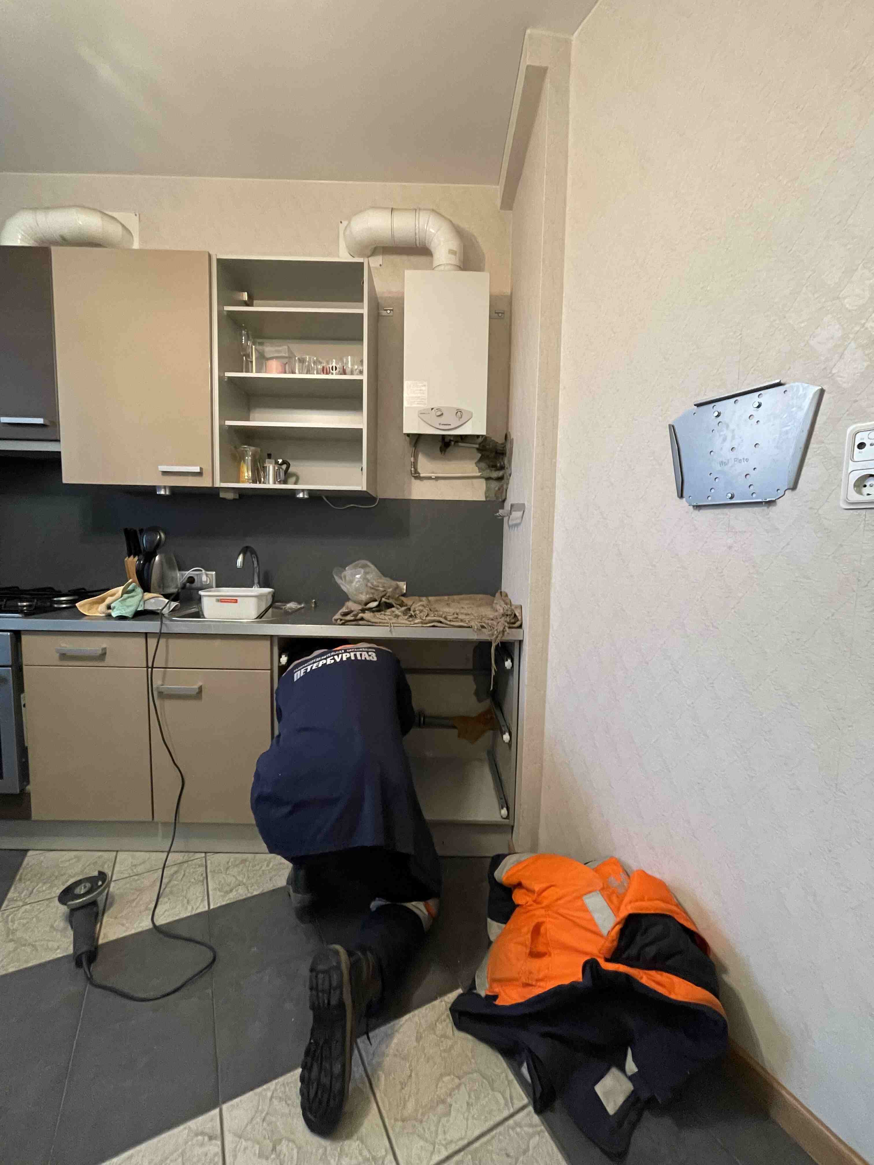 Специалист ПетербургГаза работает с подводкой под столешницей