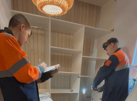Специалисты ПетербургГаза у газовой трубы внутри мебельной ниши
